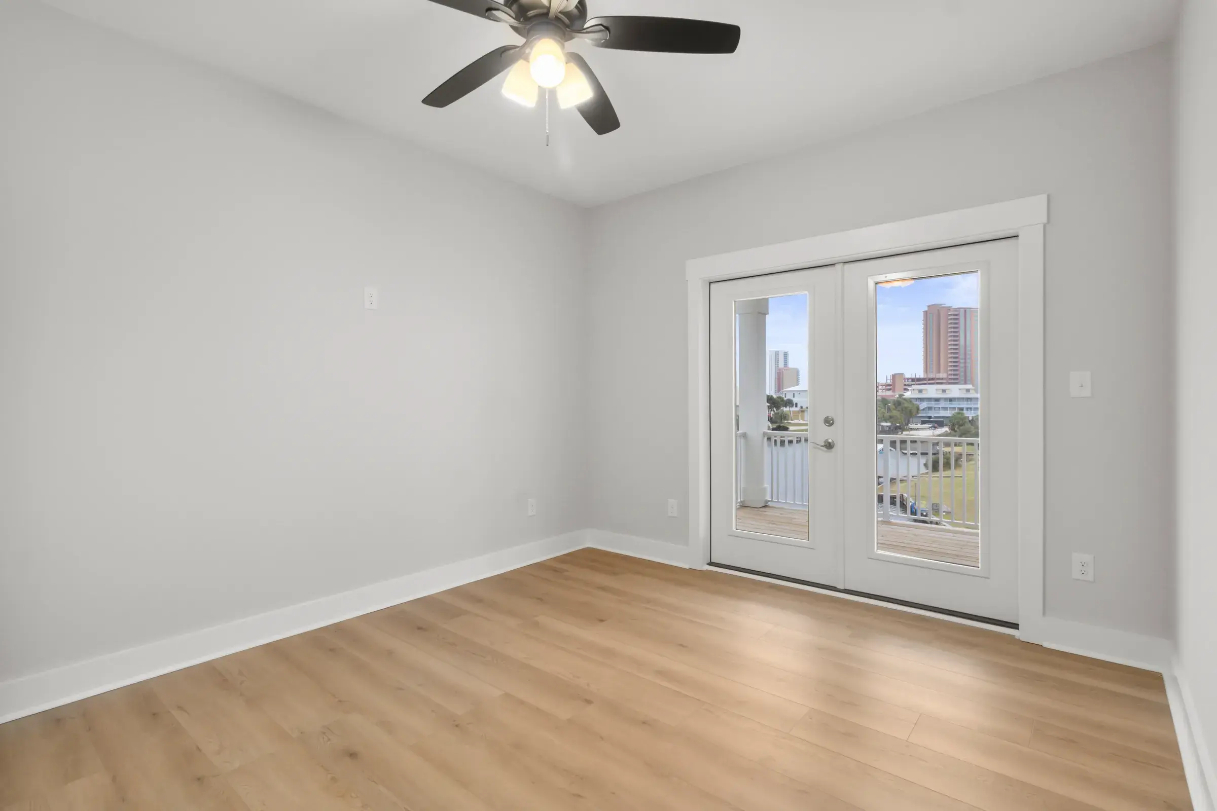 Bedroom with ceiling fan and French doors leading to a railed balcony.