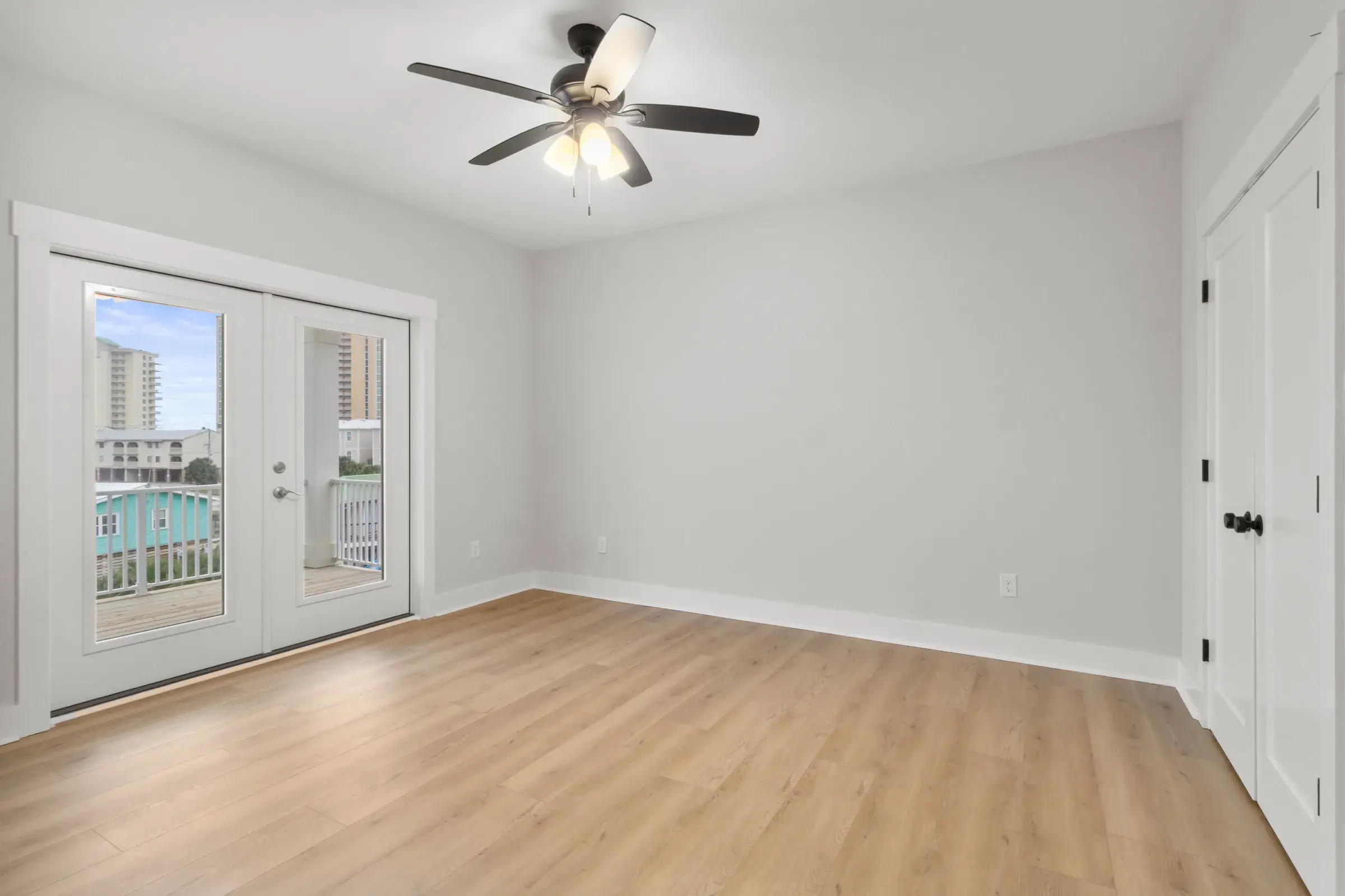 Bedroom with French doors to a balcony, a ceiling fan, and double closet doors.