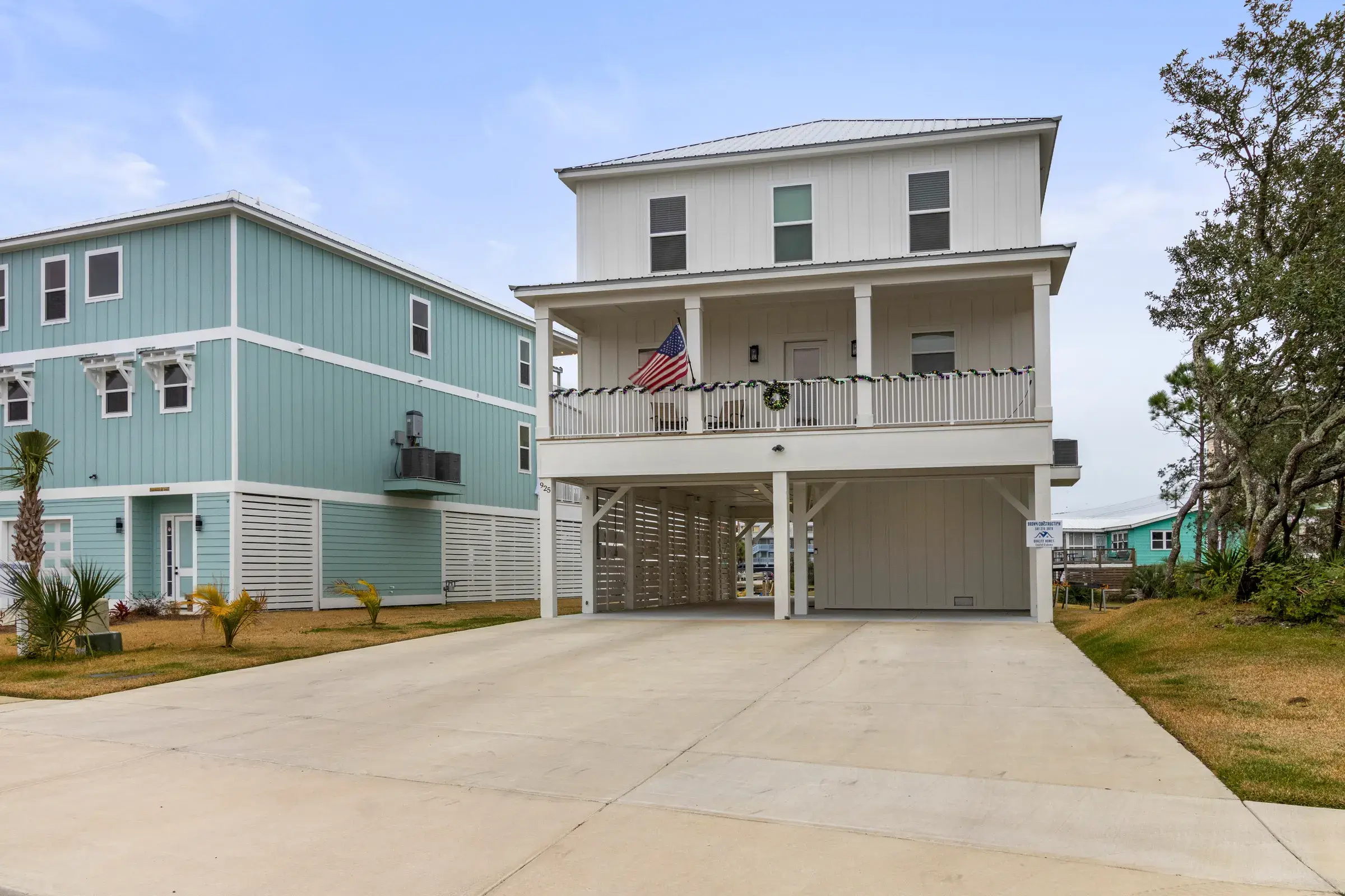 Front of the white two-story home with covered porch and parking below.
