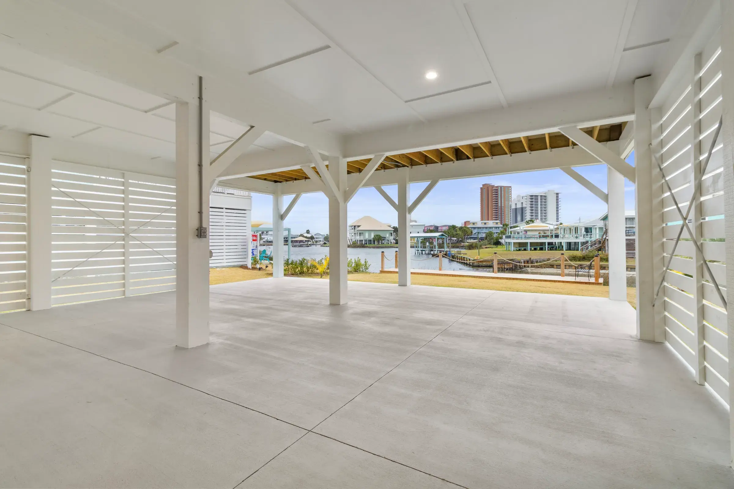 Open ground-level area looking through columns toward the lagoon, lawn and boardwalk.