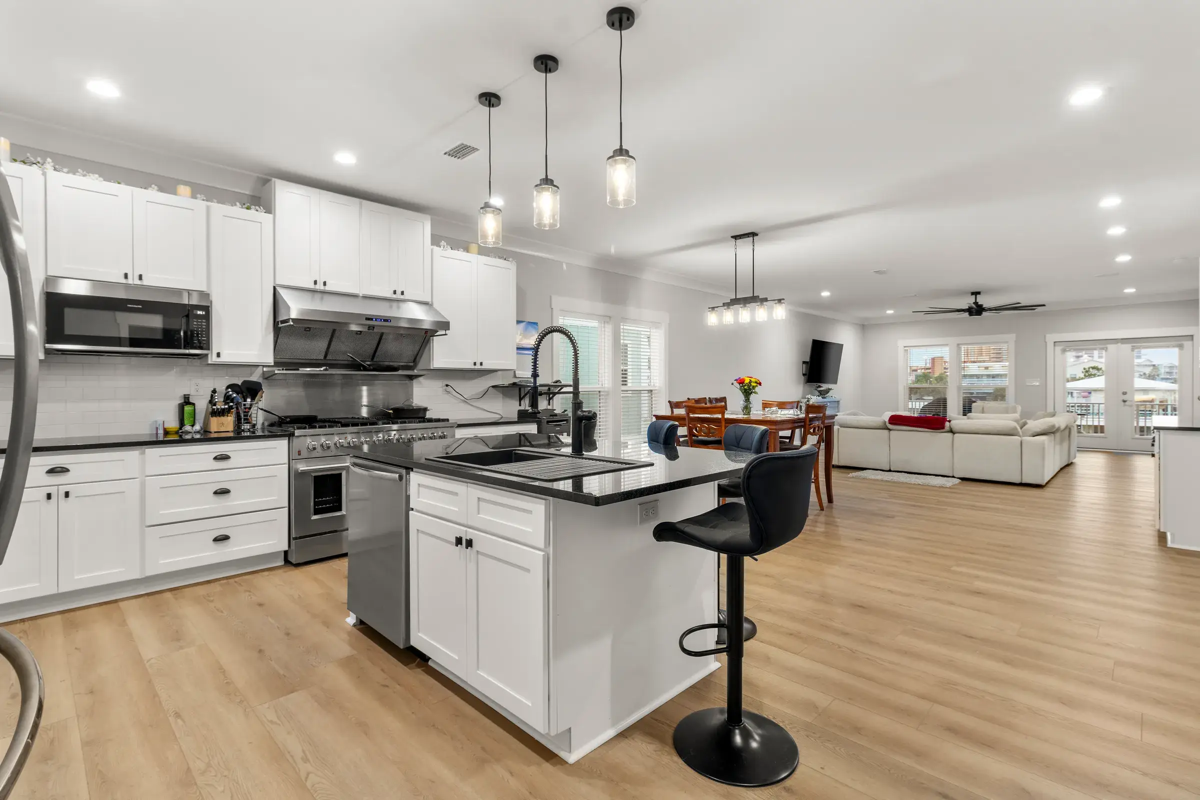 Kitchen island in the foreground with the dining and living area stretching toward French doors beyond.