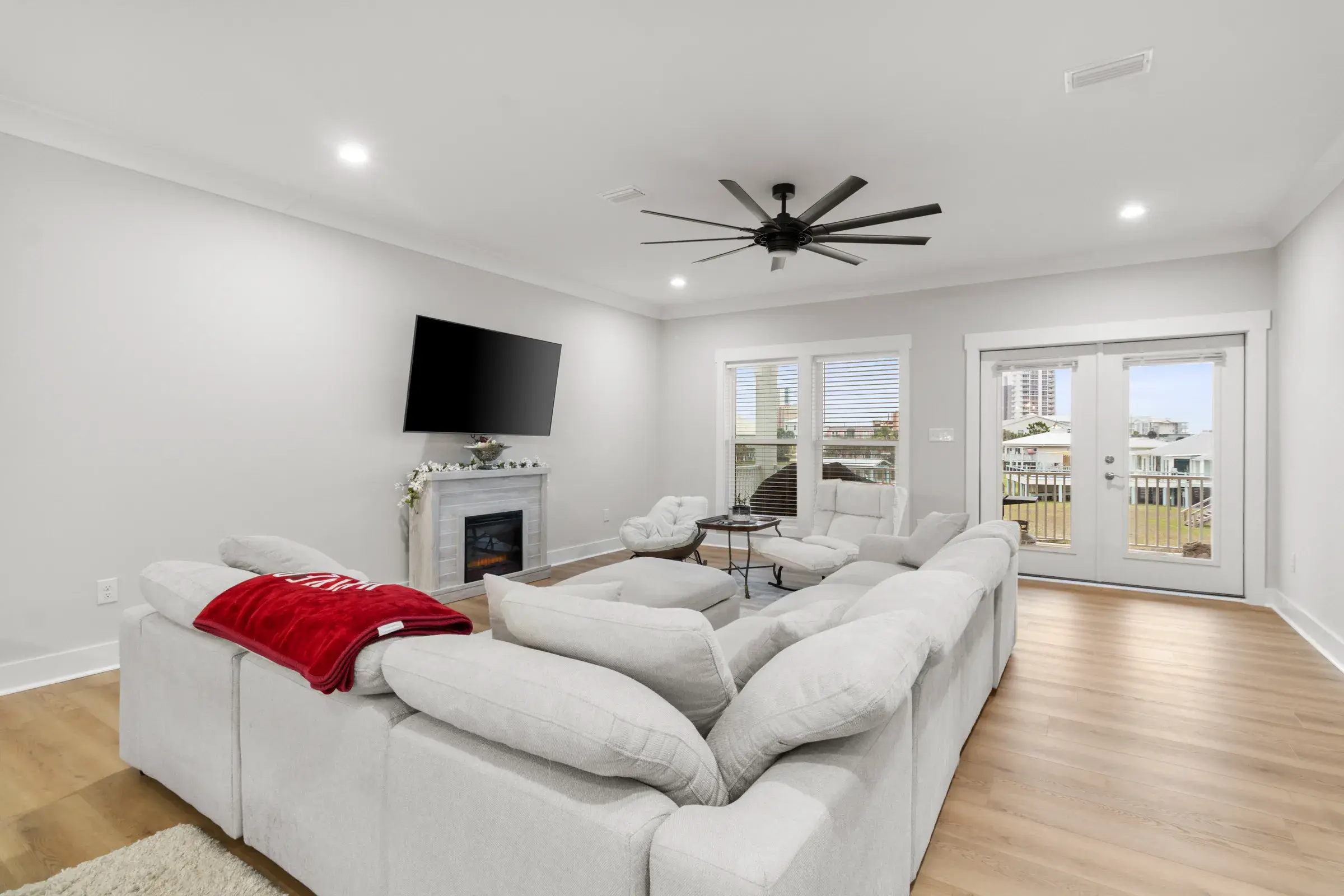 Living room with a large sectional, wall-mounted TV over a fireplace, and French doors to the porch.
