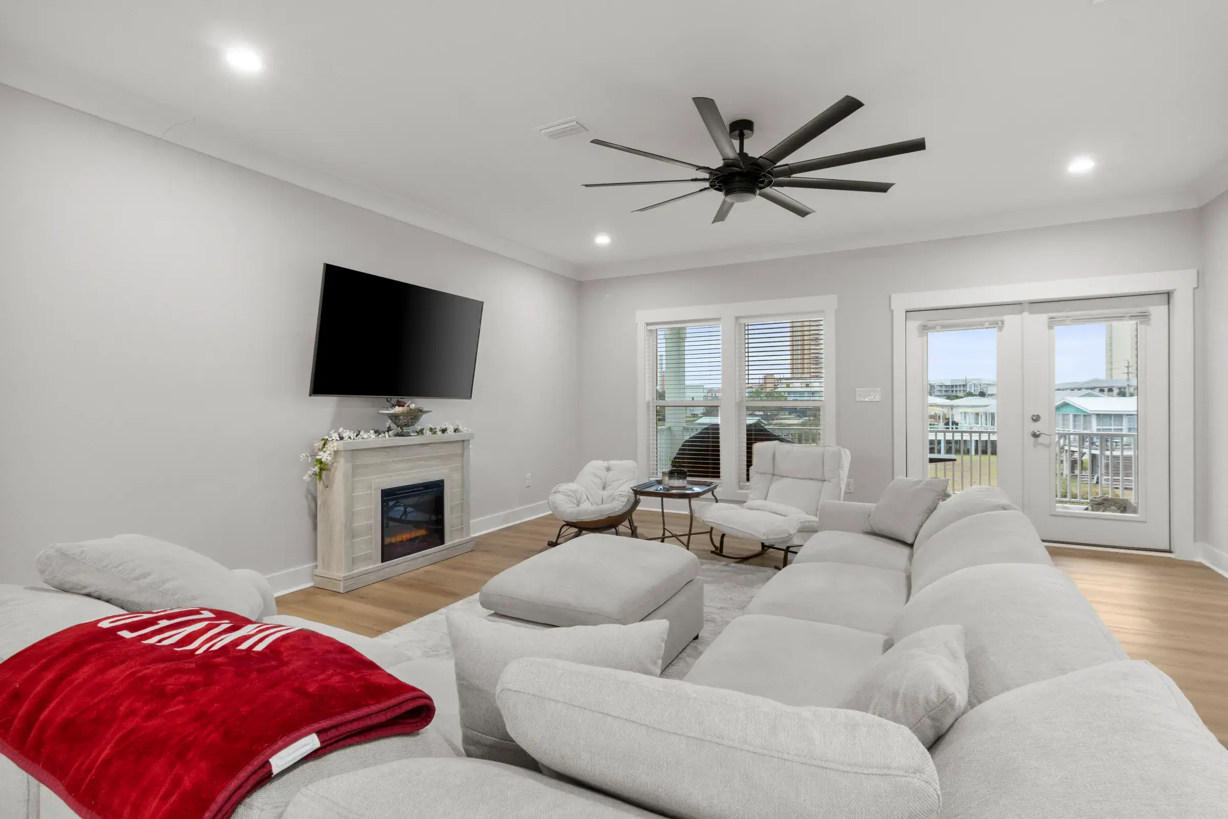 Bright living room with a gray sectional, fireplace with TV, and French doors to the porch.