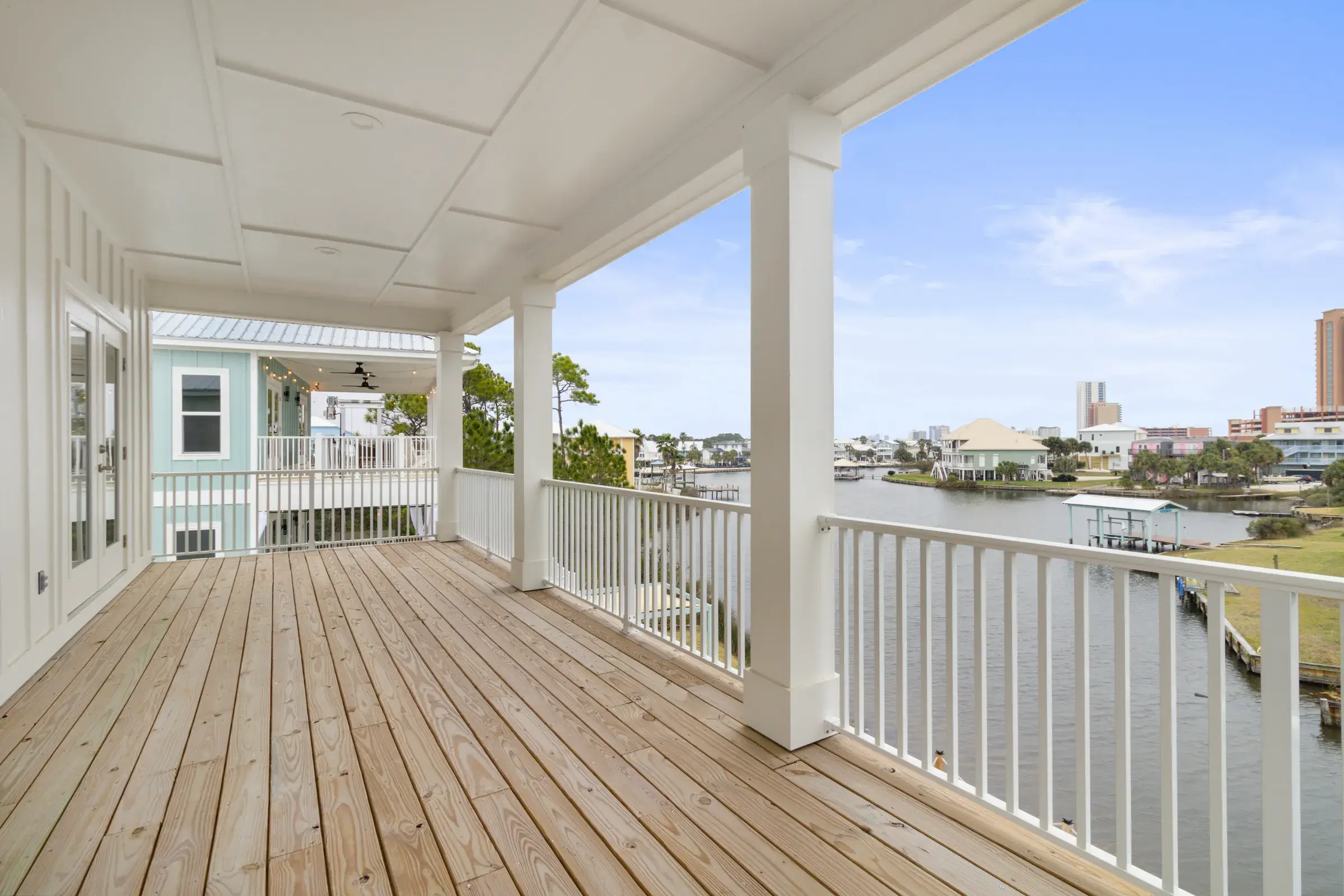 Covered wood porch with white railing and columns looking out over the lagoon.