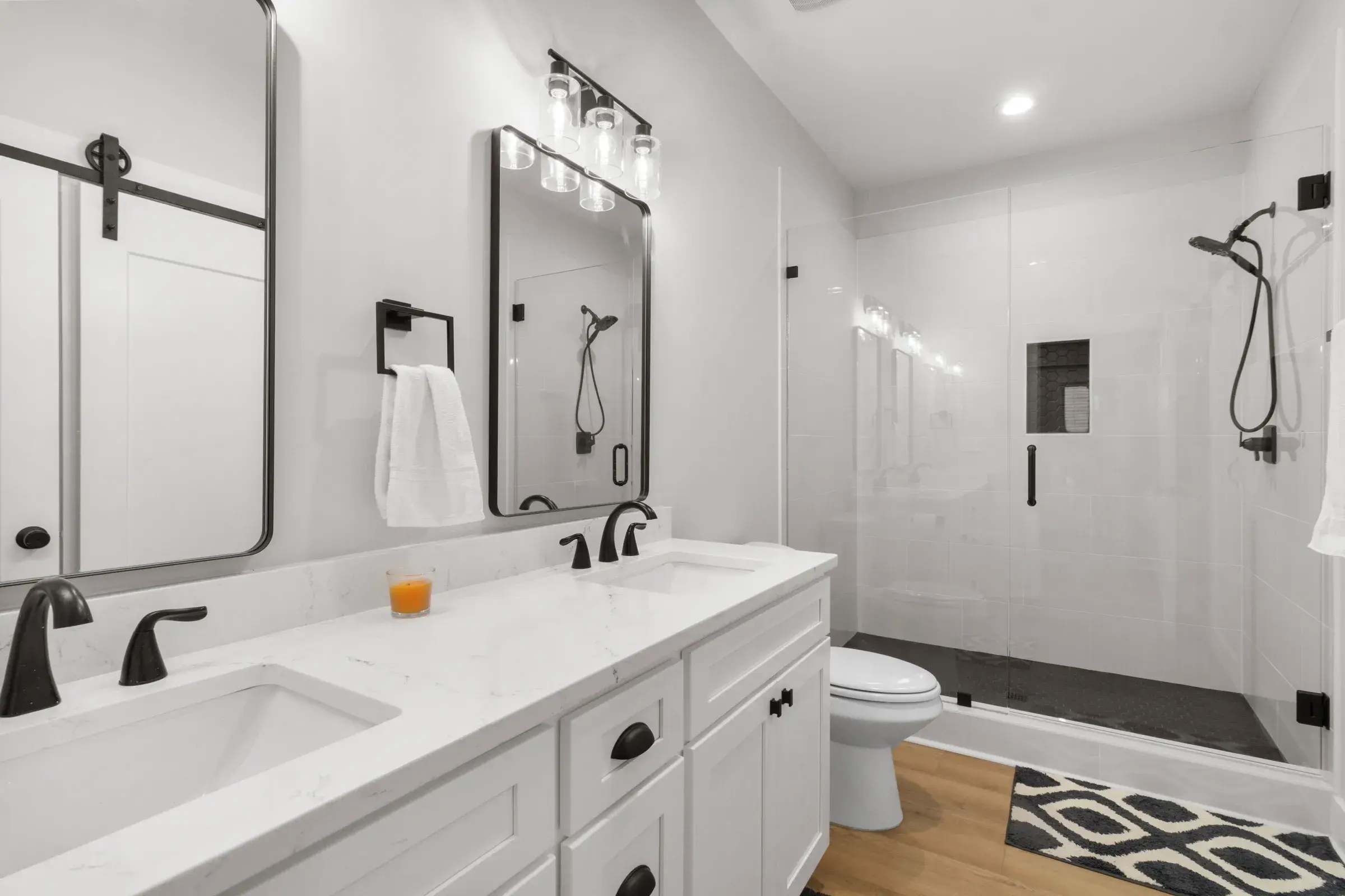 Bathroom with a white double vanity, black fixtures, and a glass-enclosed walk-in shower.